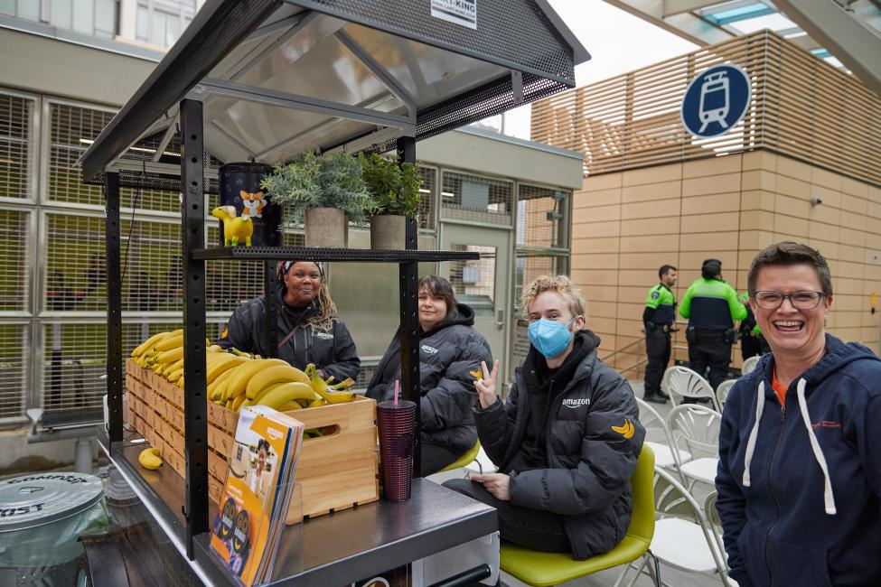 Amazon reps smile at the camera by their Banana cart
