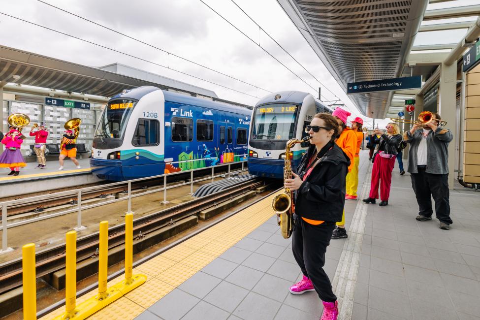 A saxophonist and other musicians perform as a train pulls up to Redmond Technology station