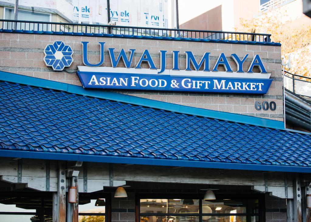 A blue sign on a building reads "Uwajimaya Asian Food and Gift Market"