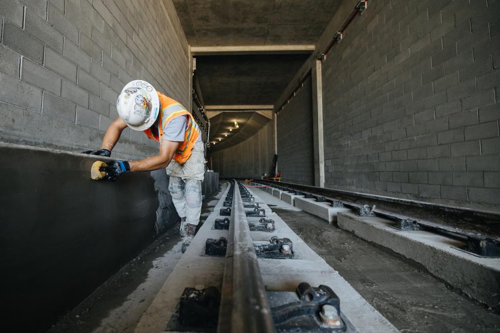 A Mason smoothing the concrete along one of the maintenance/emergency walkways inside the new Bellevue tunnel. 