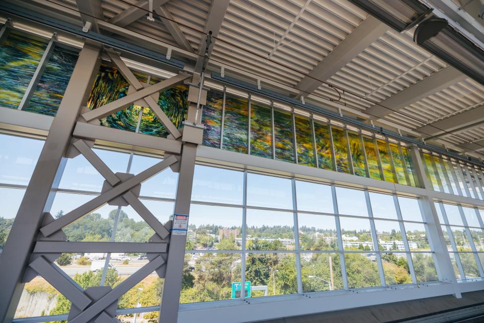 Green and yellow stained glass art is seen from the platform at Northgate Station.