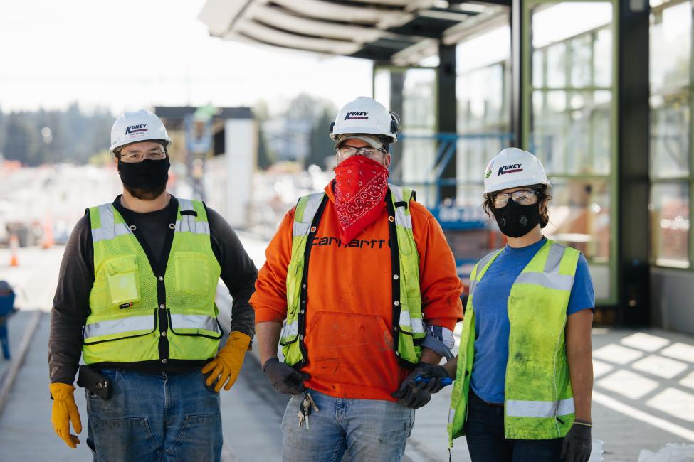 Three construction workers wear masks.