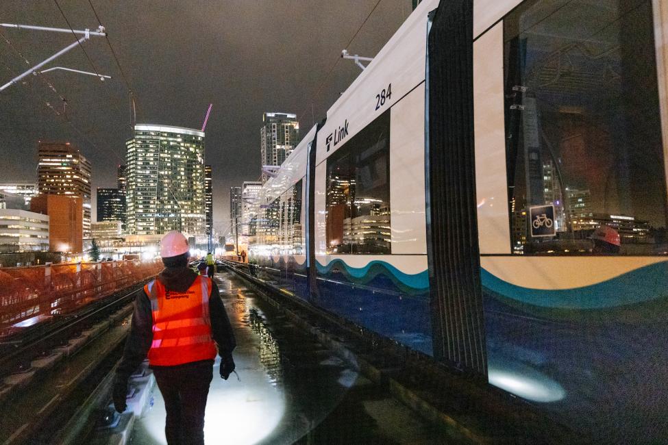 Part of the testing crew walks near the train as it slowly approaches downtown Bellevue on a recent overnight test. The trains are being pushed by a special high-rail vehicle at walking speed.