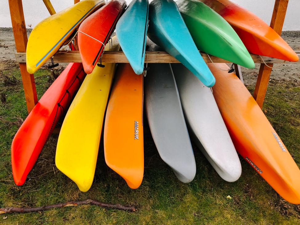Kayaks in yellow, blue, gray, green, orange and red on a rack