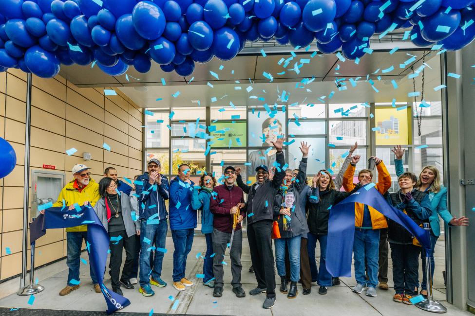 Sound Transit staff members cut the ribbon to celebrate the 2 Line opening, with balloons and confetti above their heads
