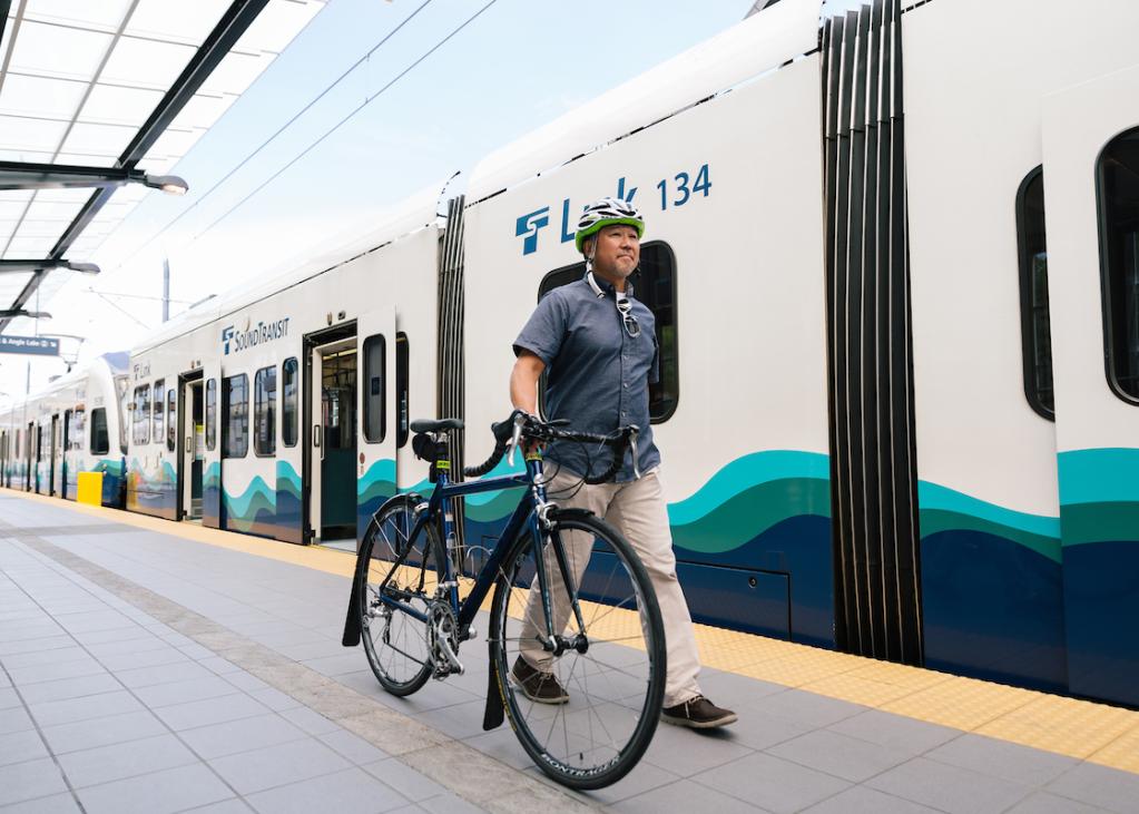 A rider approaching Link train at Angle Lake Station with his bike.