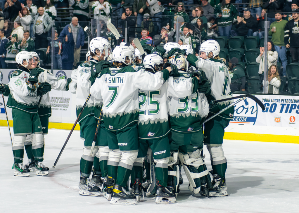 A group of Everett Silvertips huddle together as they celebrate a goal.