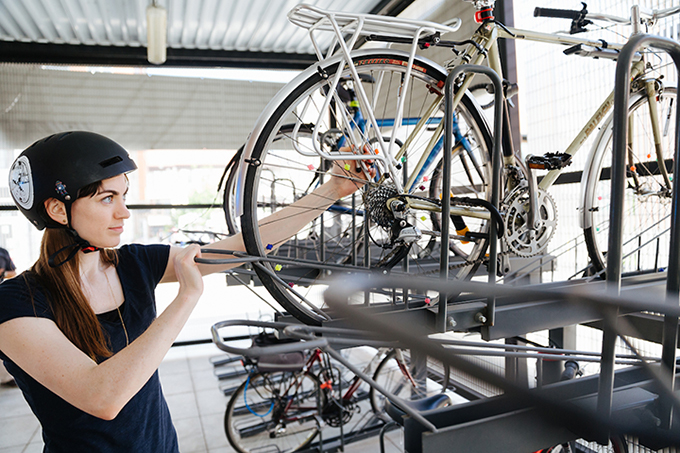 A person loading their bicycle into the storage area of a Sound Transit bike room.