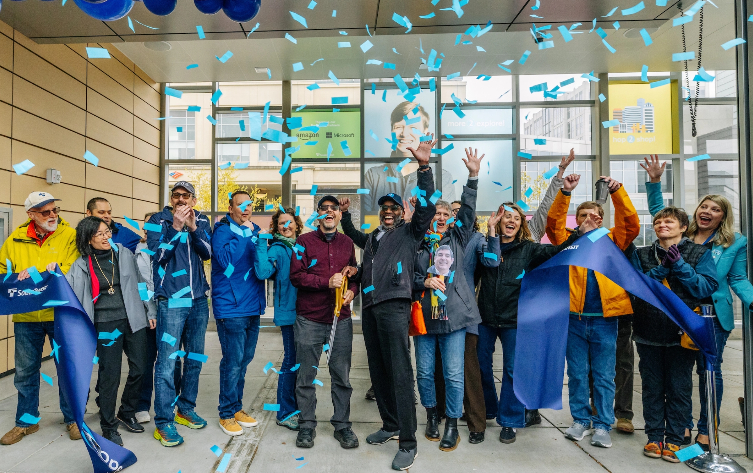 A group of people celebrate the opening of the Sound Transit 2 Line with a ribbon cutting.
