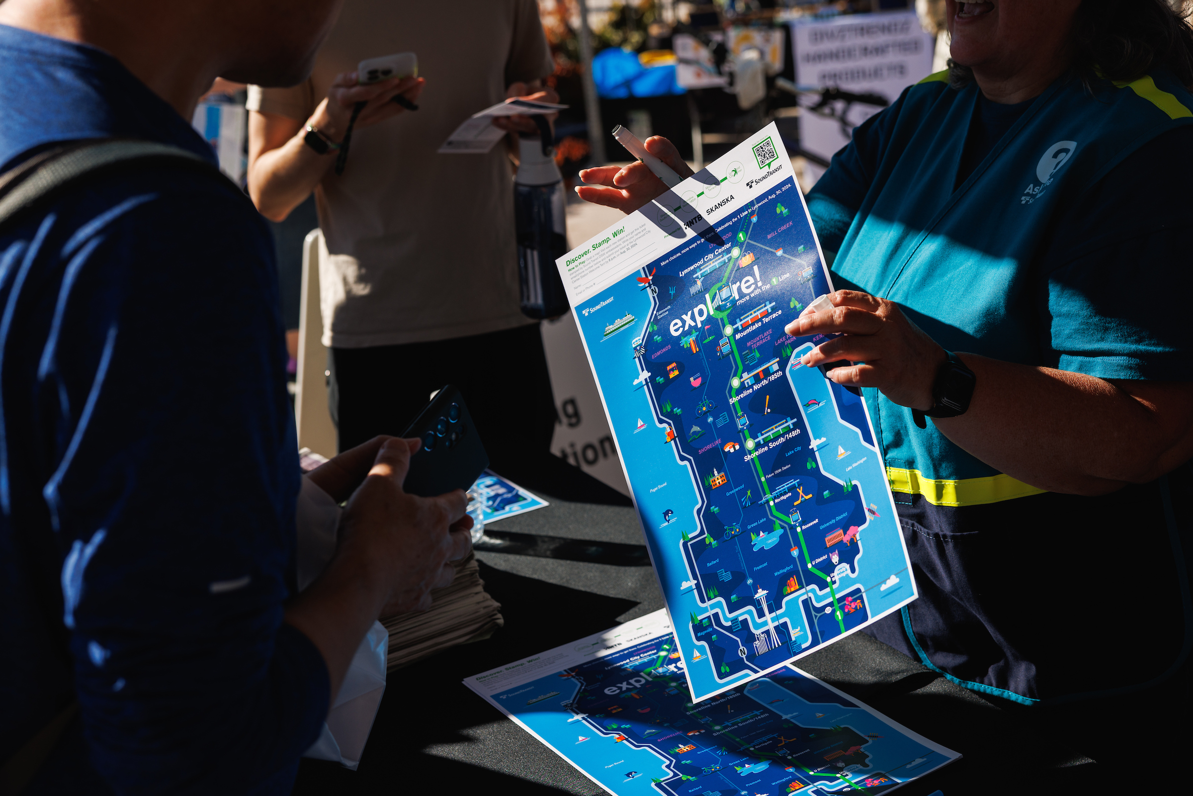 A Sound Transit ambassador holds up a poster on opening day of service in Lynnwood.