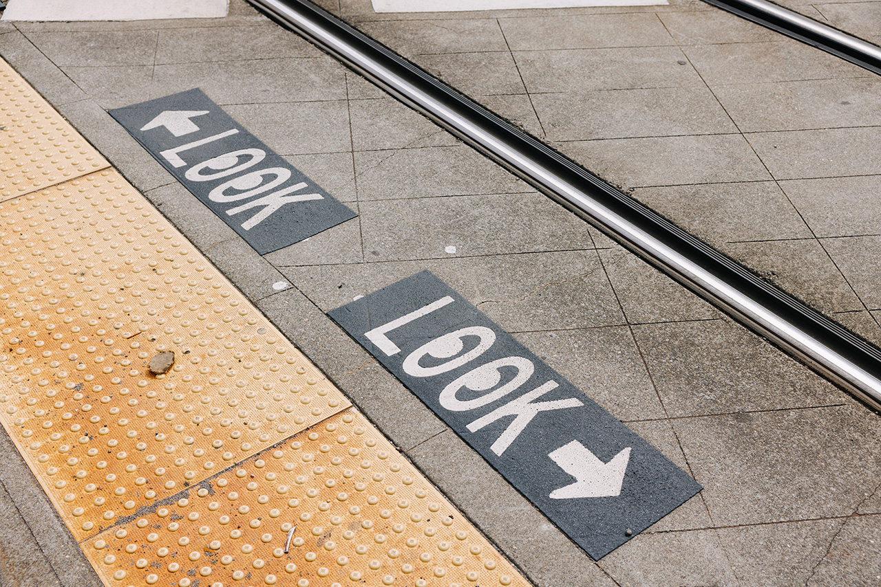 The word Look with an eyeball emoji is painted onto the street next to Link light rail tracks.