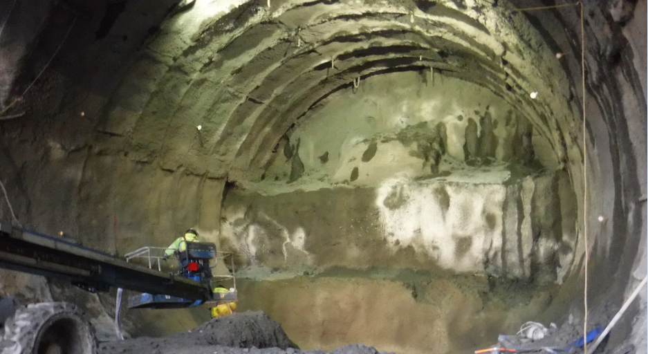 Recently exposed soil is stabilized with pressurized concrete before excavation continues. The steel, rib-like structures forming a ring around the tunnel are called lattice girders and provide additional support.