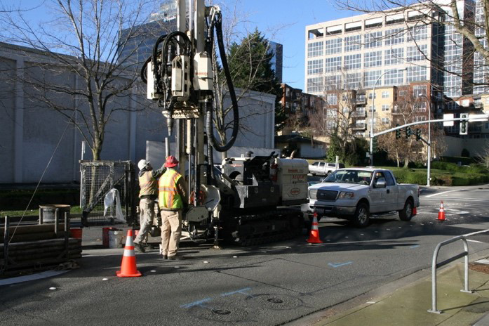 A construction crew uses geotechnical drilling equipment.