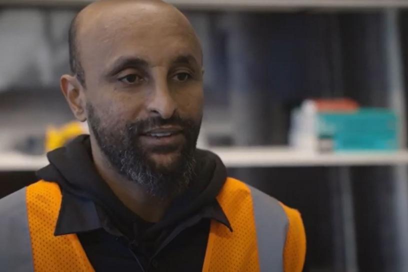 Edekel Deglel, pre-apprentice, is shown in a closeup headshot wearing an orange construction vest 