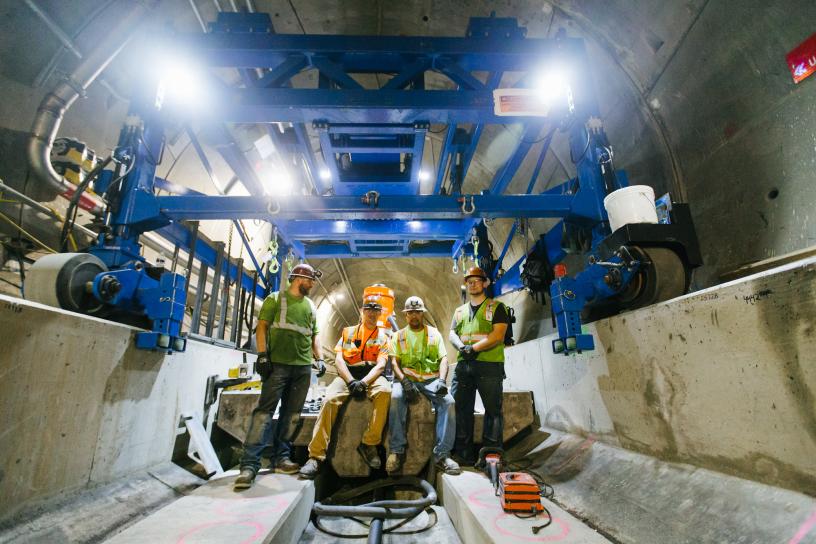 A construction crew poses beneath the special machinery (gantry truss) that lowered each of the 1,578 slabs into place in the tunnels.
