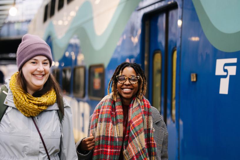 Photo of two passengers next to the Sounder Train at King Street Station