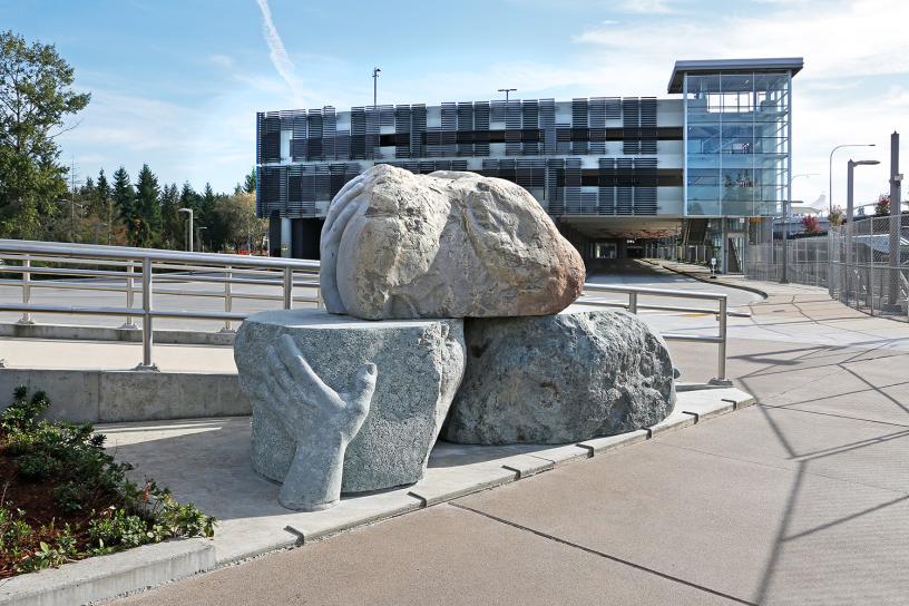 A sculpture of three boulders with large hands outside Redmond Technology Station