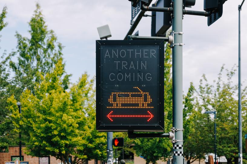A light-up warning sign alerts passengers when a second train is coming. This "Another Train Coming" sign is a part of the safety enhancements the At-Grade Crossing Program has added near light rail.