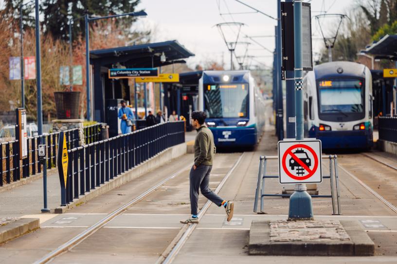 A pedestrian crossing the tracks at Columbia City Station. Note pedestrian safety improvements made by the at-grade crossing program