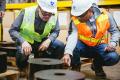 Moises Gutierrez, left, and Shankar Rajaram from the Sound Transit engineering team inspect the specially-sourced rubber pad that each floating slab rests upon. 