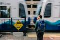 A passenger standing next to a look both ways sign waits for a train to pass at SODO Station. 