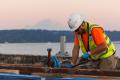 A worker on the I-90 bridge at sunset, with Mount Rainier in the background