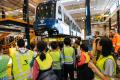 A group of young people in yellow vests look at a Link train in an OMF