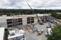 An aerial view of the Sumner Station parking garage under construction. The multi-level concrete structure is taking shape next to the Sounder station platform, with construction equipment, materials, and a freight train visible alongside the rail corridor.