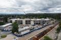Aerial view of the Sumner Station parking garage construction site showing the nearly completed concrete structure, construction vehicles, materials staging areas, and workers building the upper levels adjacent to the rail station.