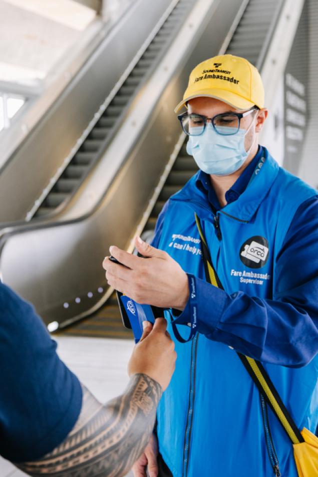 Photo of a fare ambassador using a handheld device to verify fare payment