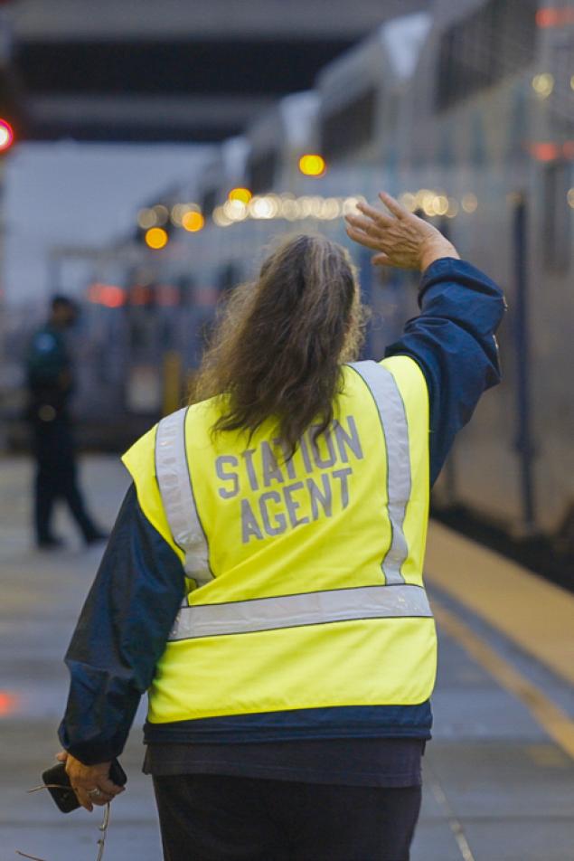 Photo of a station agent in a yellow vest with the words "Station Agent" printed on it
