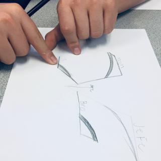 Hands point to the family tree drawn on a piece of white paper with a pencil