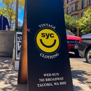 Sandwich board sign for syc out on the sidewalk in the sunshine in front of the shop