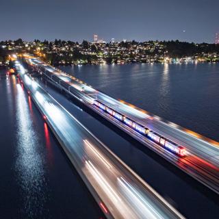 The blur of a train crosses the I-90 bridge in the evening