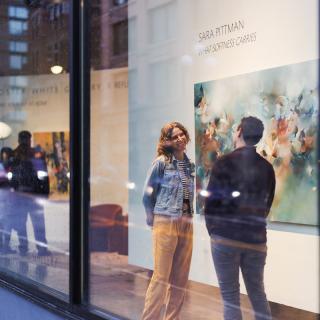 A couple stands in the window of the Foster/White Gallery in Seattle