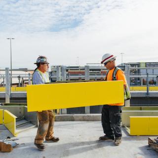 Workers carrying yellow panels on the platform of the future Northgate Link light rail station