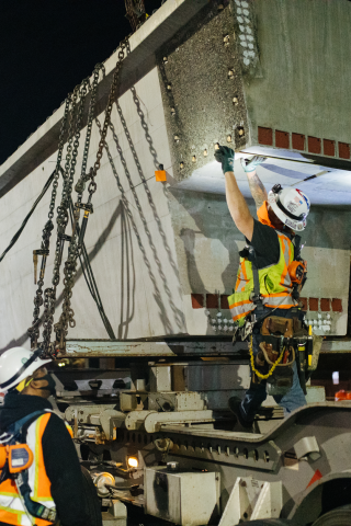 Construction crew preparing light rail concrete girders for placement.