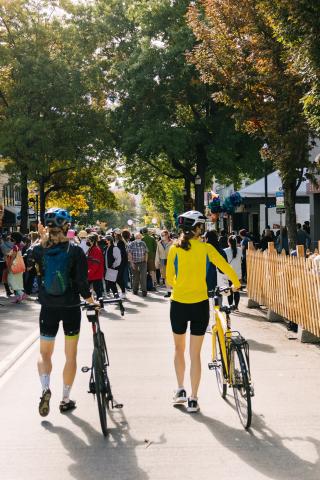 Two people walk their bicycles through a street festival in the U District neighborhood