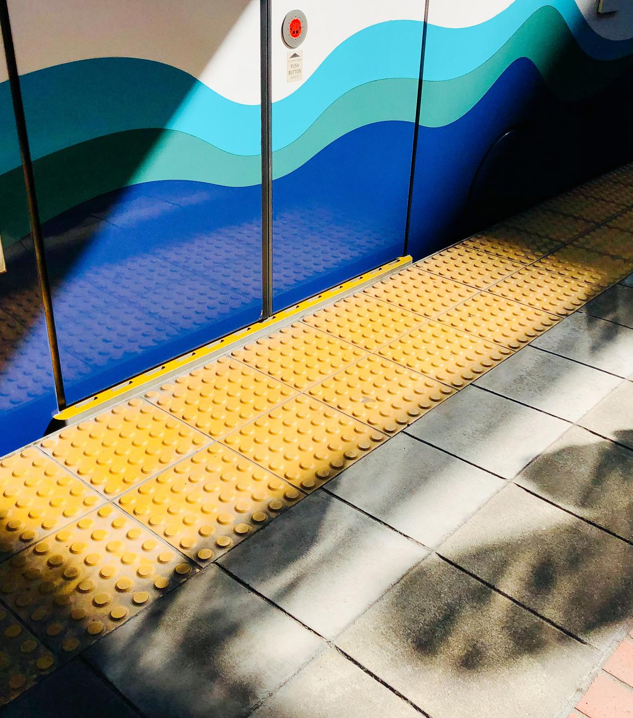 A Link light rail train at a station platform with a mix of sun and shade.