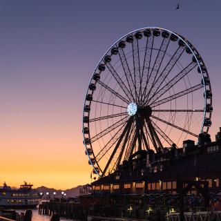 The dark outline of Seattle's Great Wheel against an orange and purple sky