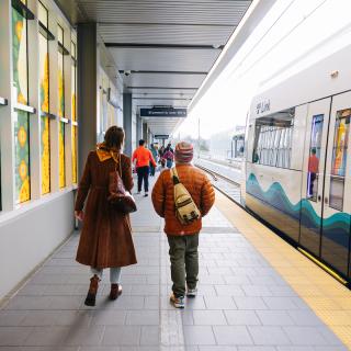 Two people with backpacks walk along the platform at Star Lake Station