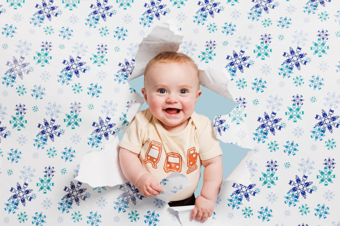 A baby surrounded by Sound Transit holiday wrapping paper.