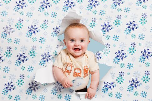 A baby surrounded by Sound Transit holiday wrapping paper.