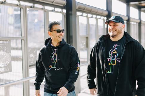 Two people wearing shirts with Puget Sound area light rail extensions displayed.