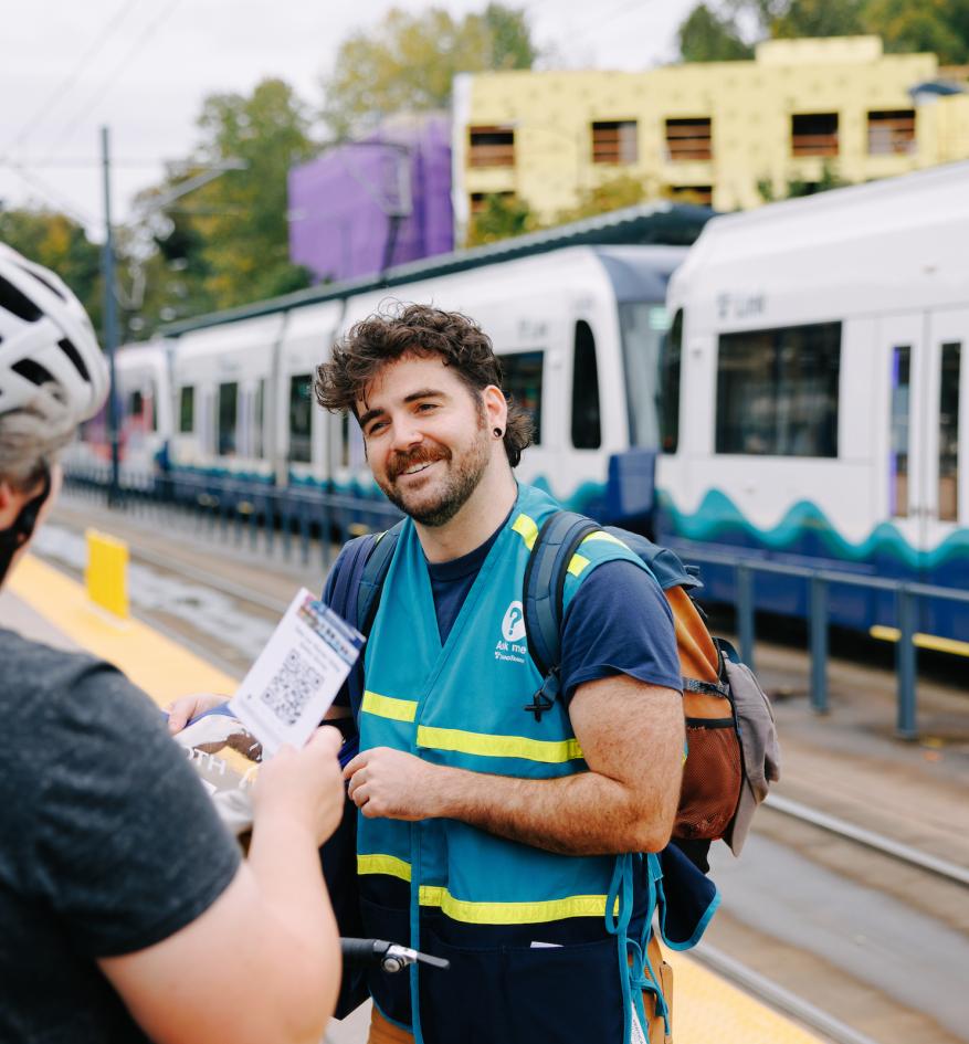 A Sound Transit staff ambassador helps a passenger at a Link station