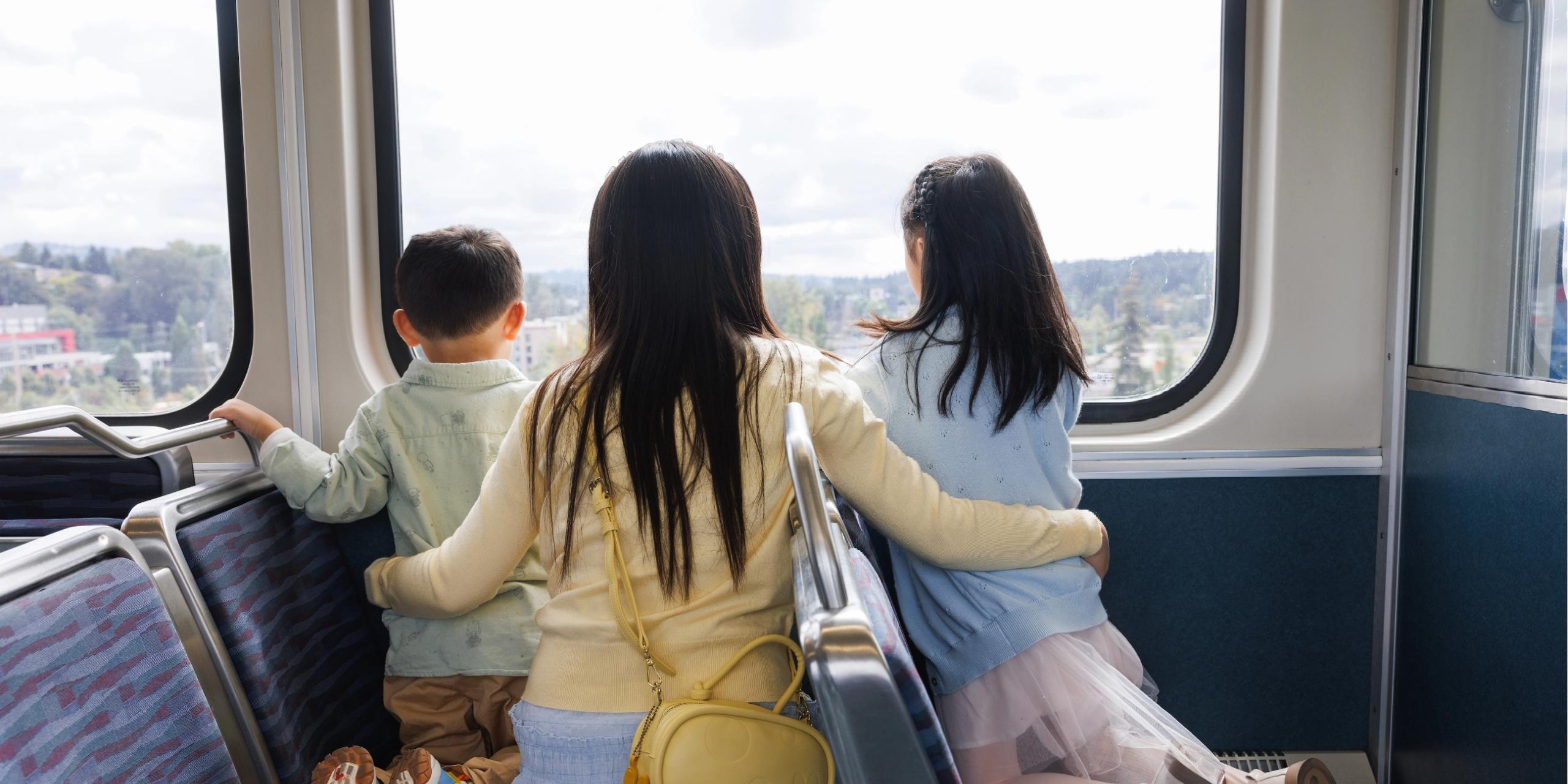 A family looks out the window of a Link light rail train.