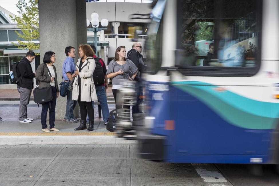 people waiting at cross walk as bus turns