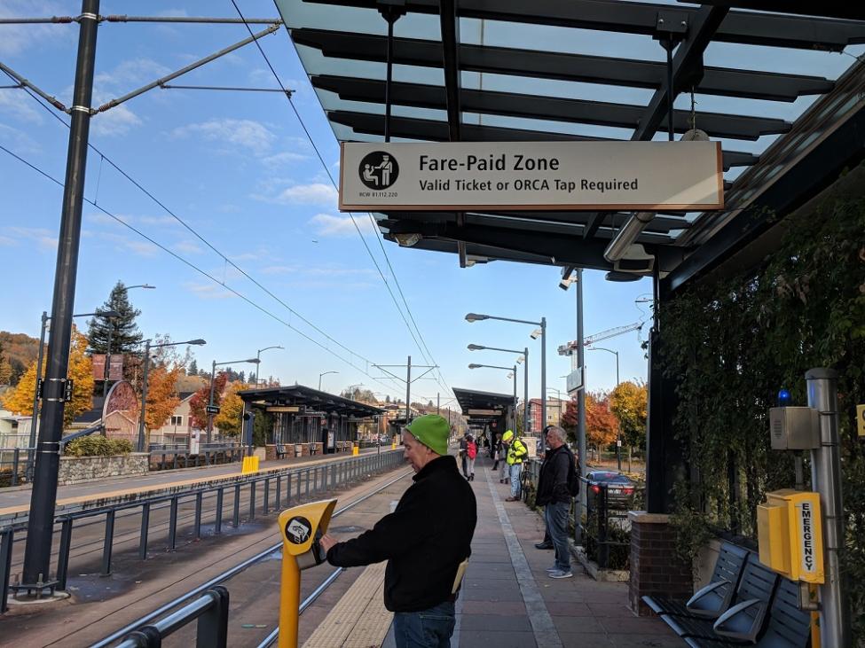 A rider taps his ORCA card at the reader at the Columbia City Link light rail platform