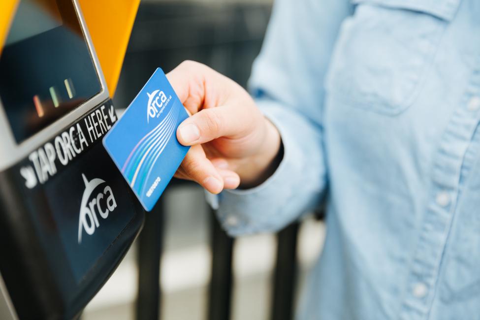 A rider tapping their ORCA card before boarding a train