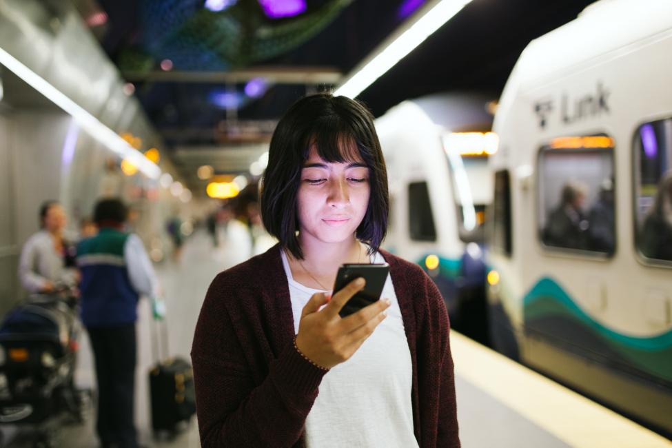 2018 in review: a rider browsing on her cell phone at the Beacon Hill Station thanks to new cell service starting at the station.